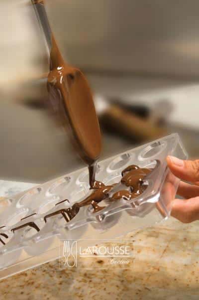 <p>Llenar los moldes con chocolate fundido y temperado, golpearlos vigorosamente sobre la mesa haciendo movimientos pequeños y repetitivos para sacar todas las burbujas de aire. Dejar el chocolate en los moldes por unos momentos.</p>
