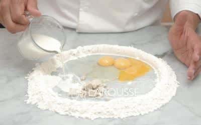 <p>Forme con la harina un círculo sobre una superficie plana y añada dentro, en una de las orillas, la leche con la levadura, y del lado opuesto, el huevo, las yemas y la sal. Disuelva la levadura en la leche, y mezcle el huevo y las yemas con la sal.</p>
