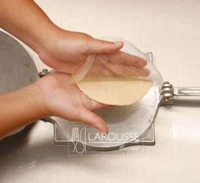 <p>Levante la tortilla junto con el plástico de abajo; con una mano ponga la tortilla sobre los dedos de la otra mano y retire el plástico.</p>
