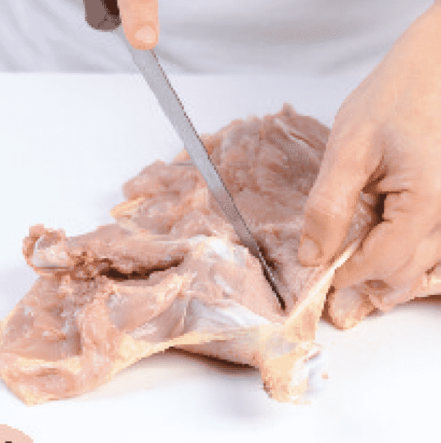 <p>Corte la carne que rodea el hueso del muslo. Una vez que haya dejado a la vista el hueso, gire el pollo para facilitar los cortes.</p>
