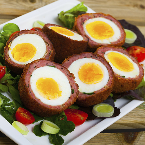 Huevos escoceses servidos con verduras y puerro